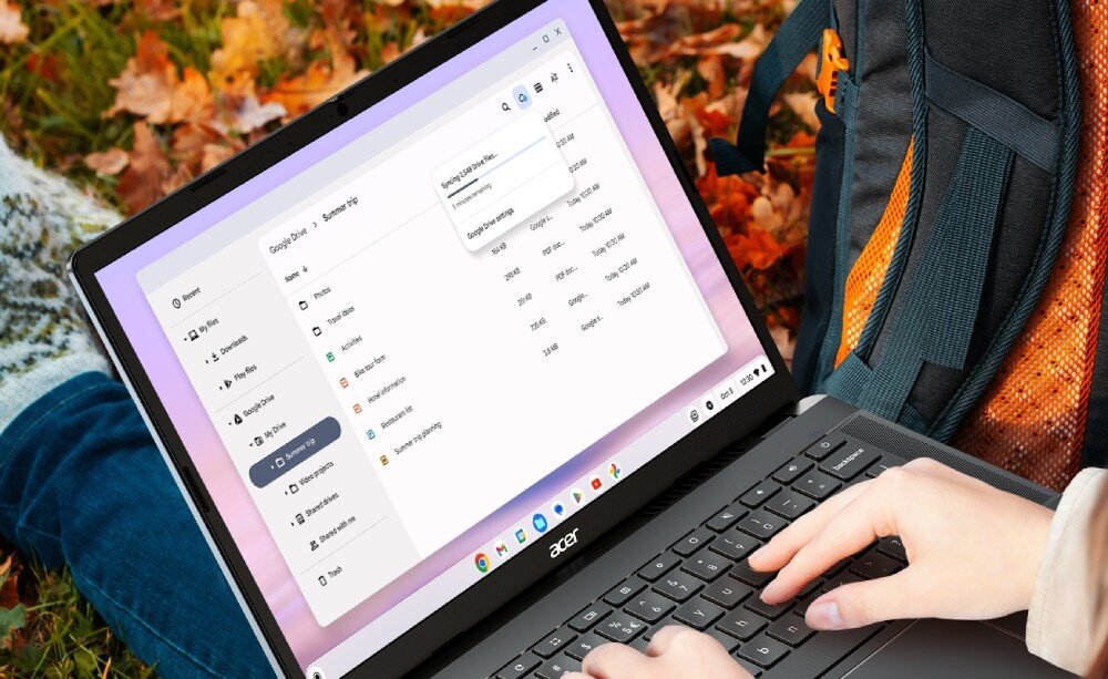 Laptop ACER Chromebook Plus 514 CB514-3H-R36J Osoba siedząca na zewnątrz jesienią pracuje na laptopie z otwartym folderem 'Google Drive' na ekranie, obok widoczny plecak, synchronizacja plików