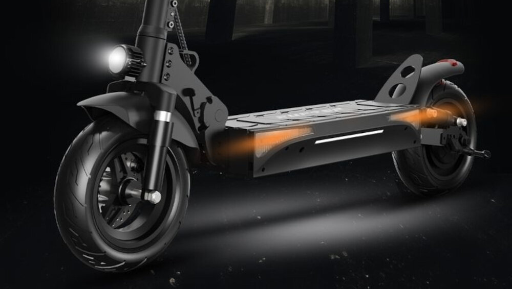 Czarna hulajnoga elektryczna z widocznym przednim i tylnym kołem oraz podświetleniem na podeście. W tle ciemne otoczenie z niewyraźnymi elementami architektonicznymi.