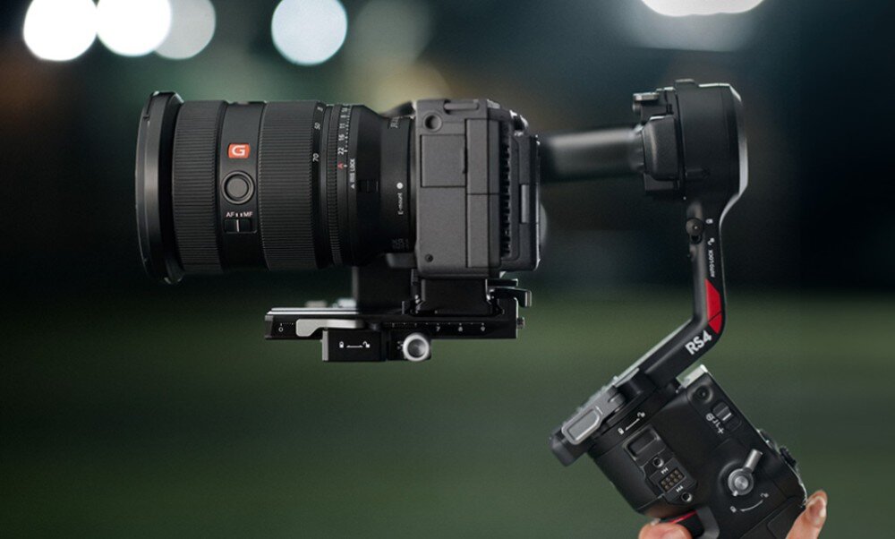 Osoba trzyma gimbal z zamontowanym aparatem fotograficznym. Na gimbalu widoczny jest napis \'RS 4\'.