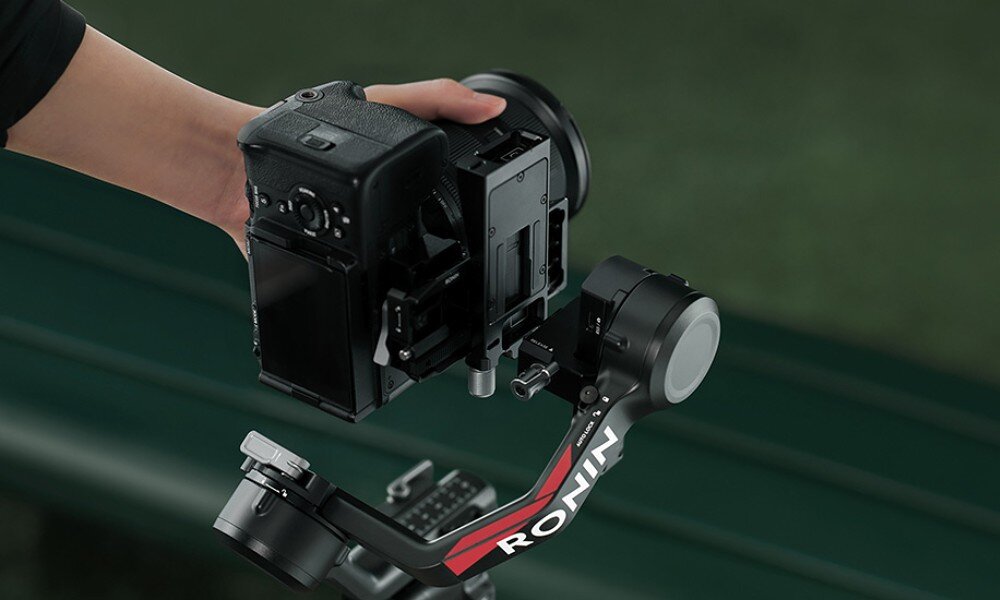 Osoba trzyma aparat zamontowany na gimbalu z widocznym napisem \'RONIN\'.