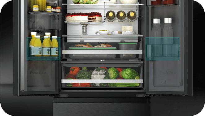 Otwarta lodówka z widocznymi półkami, na których znajdują się różne produkty spożywcze, w tym butelki, ciasto i warzywa. Na szufladzie widoczny napis \'Fruit & Veggie\'.