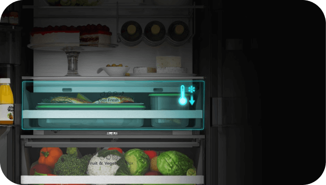 Wnętrze lodówki z widocznymi półkami i szufladami, na których znajdują się różne produkty spożywcze. Na szufladzie widoczny napis: \'Fruit & Vegetable Box\'.