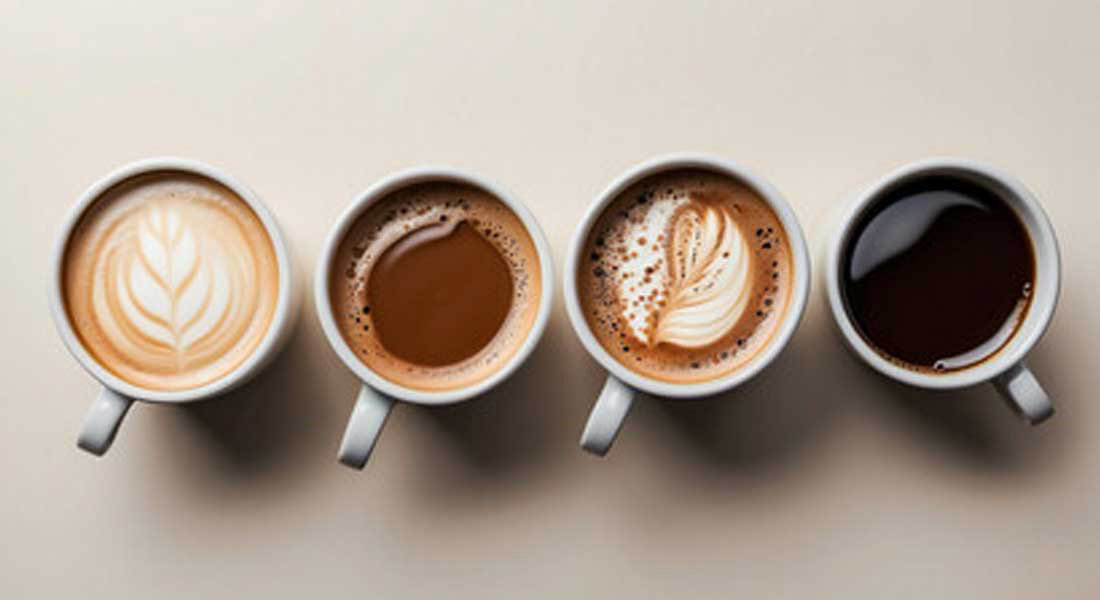 Cztery filiżanki kawy ustawione obok siebie, każda z innym rodzajem kawy i wzorem na powierzchni. Tło jest jednolite i jasne.