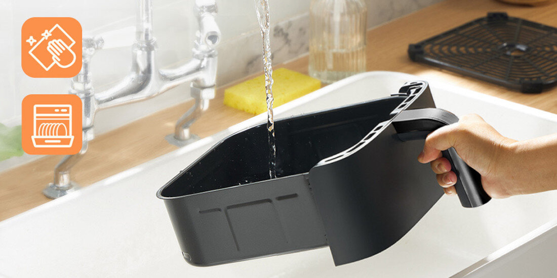 Czarna tacka jest płukana pod bieżącą wodą w zlewie. Obok znajdują się ikony wskazujące na możliwość mycia ręcznego i w zmywarce.