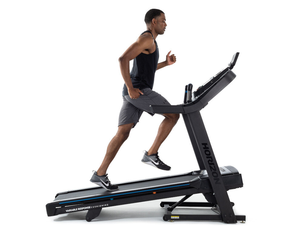 Osoba biegnie na bieżni elektrycznej z widocznym logo \'HORIZON\'. Na bieżni znajduje się napis \'VARIABLE RESPONSE CUSHIONING\'.