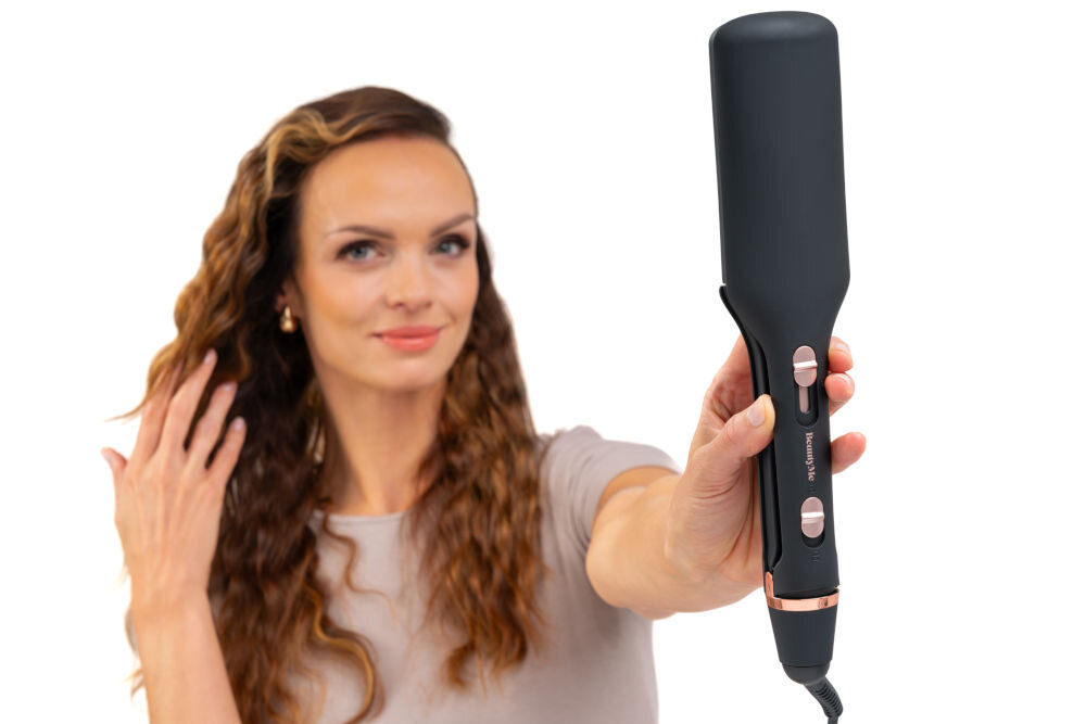 Osoba trzyma czarną falownicę z widocznymi przyciskami i logo \'BEAUTYME\'. W tle widać osobę z falowanymi włosami.