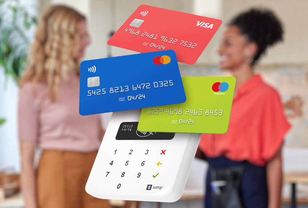 Na pierwszym planie widoczny jest terminal płatniczy z logo \'sumup\' oraz trzy karty płatnicze w kolorach czerwonym, niebieskim i zielonym z widocznymi numerami i datami ważności. W tle znajdują się dwie osoby w rozmytym ujęciu.