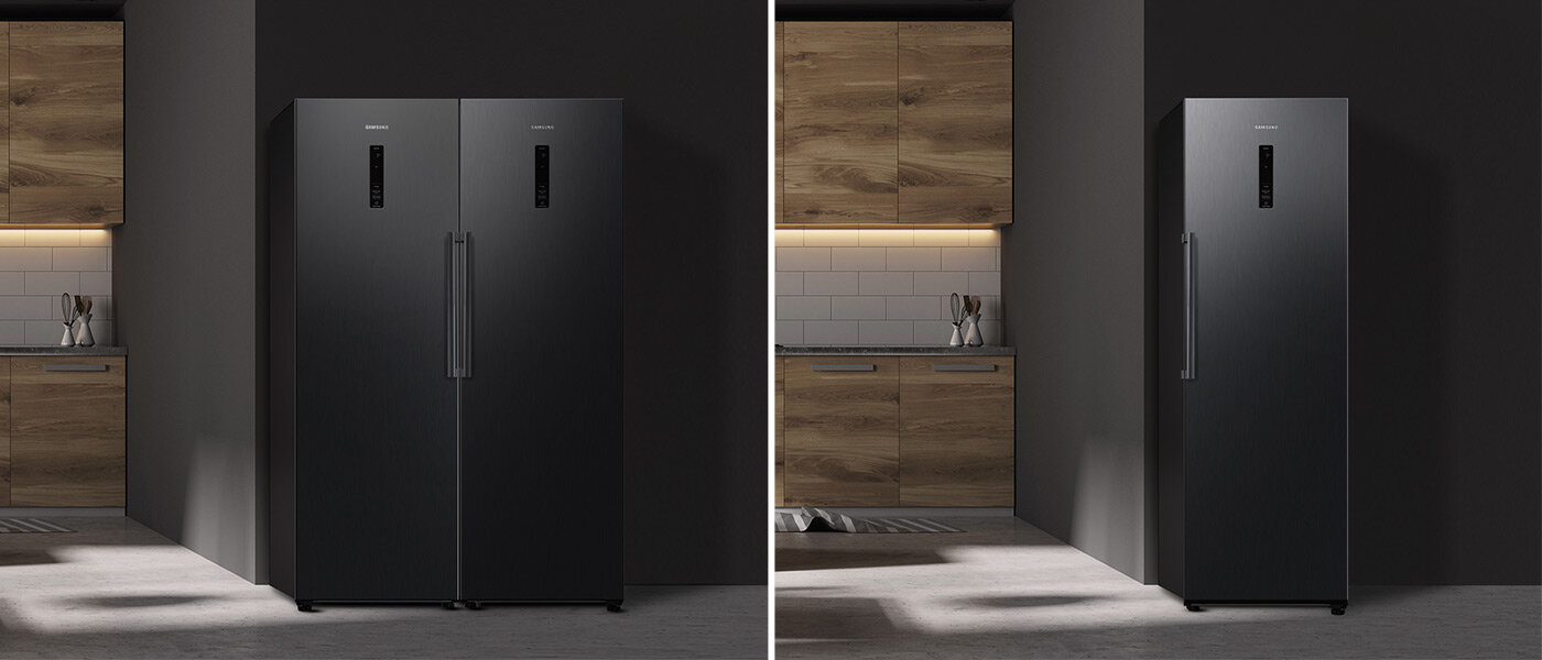 Na obrazie widoczne są dwie grafitowe lodówki w nowoczesnej kuchni z drewnianymi szafkami. Na lodówkach znajduje się logo \'SAMSUNG\'.