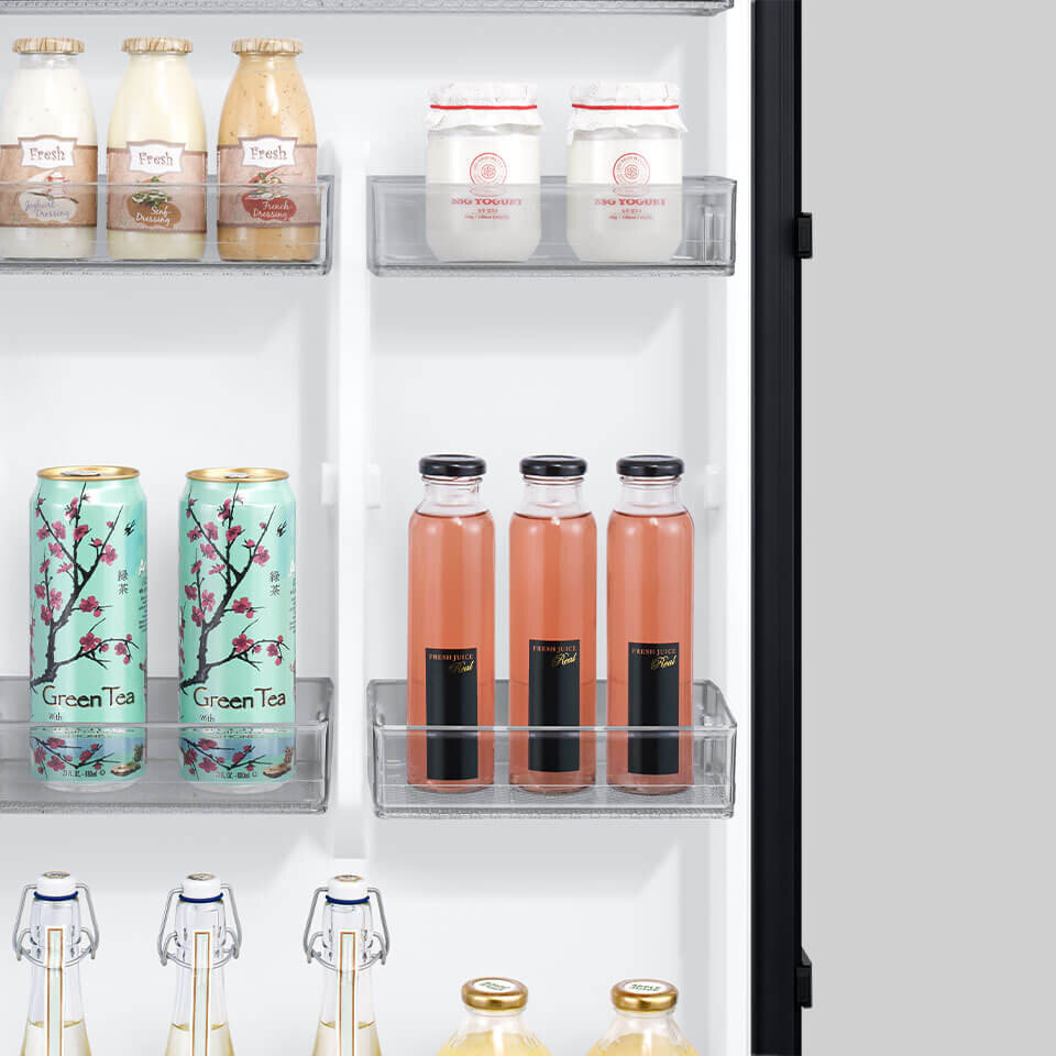 Wnętrze lodówki z widocznymi półkami, na których znajdują się różne napoje i produkty spożywcze w butelkach i puszkach. Na puszkach widoczny jest napis \'Green Tea\'.