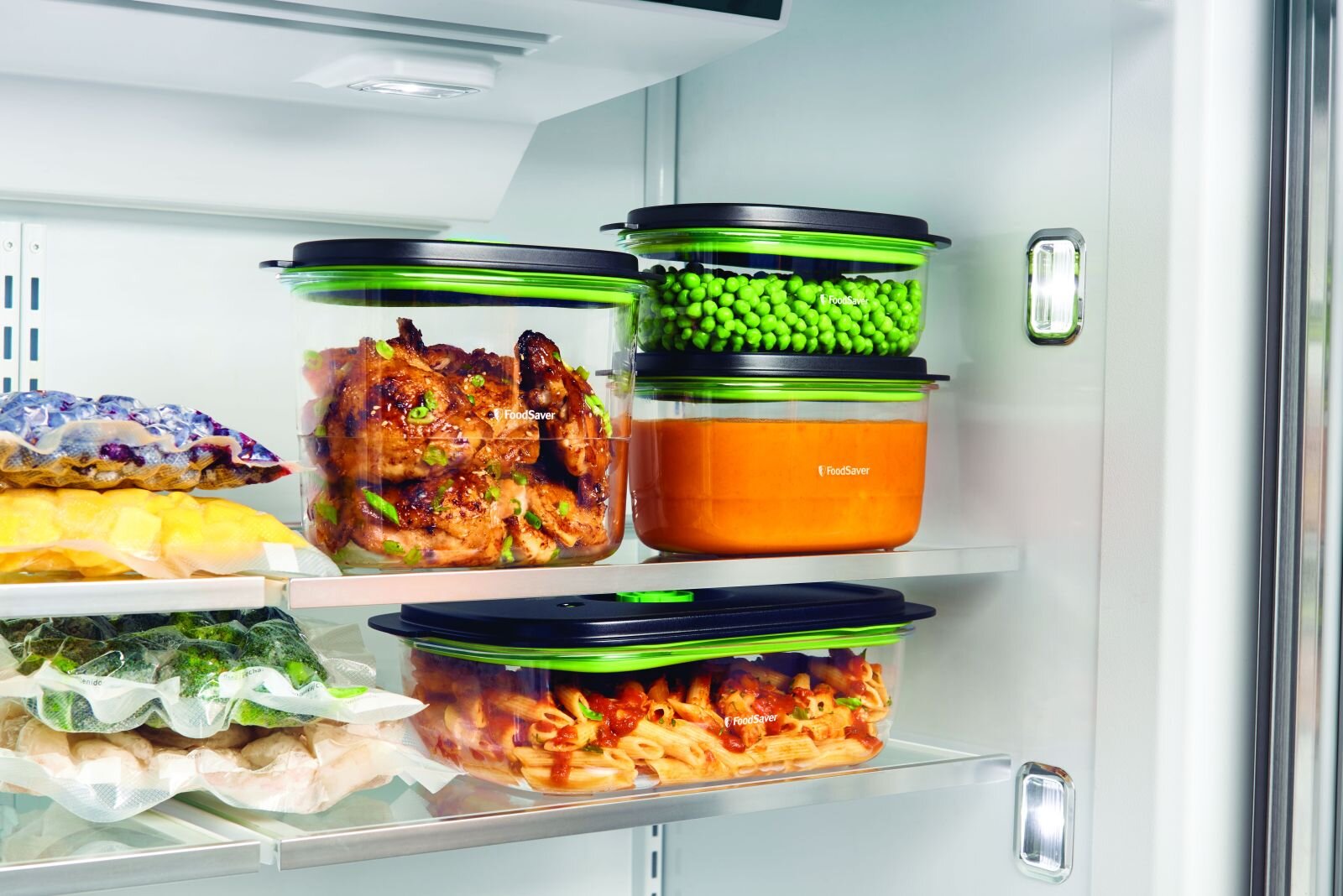 W lodówce znajdują się trzy pojemniki na żywność z czarnymi pokrywkami, wypełnione różnymi produktami spożywczymi. Na pojemnikach widoczne jest logo \'FoodSaver\'.