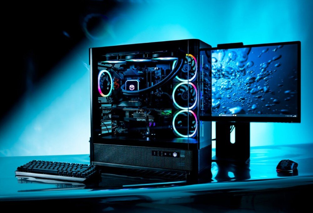 Obudowa ENDORFY Aquarius 8000 Flex Komputer stacjonarny z przeszkloną obudową eksponującą podzespoły z podświetleniem RGB stoi na ciemnym blacie obok monitora wyświetlającego grafikę z pęcherzykami wody