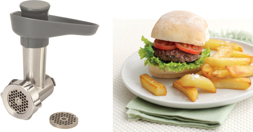 Po lewej stronie znajduje się metalowa maszynka do mięsa z szarym uchwytem i dodatkowym sitkiem. Po prawej stronie widoczny jest talerz z burgerem, frytkami i zieloną serwetką pod spodem.