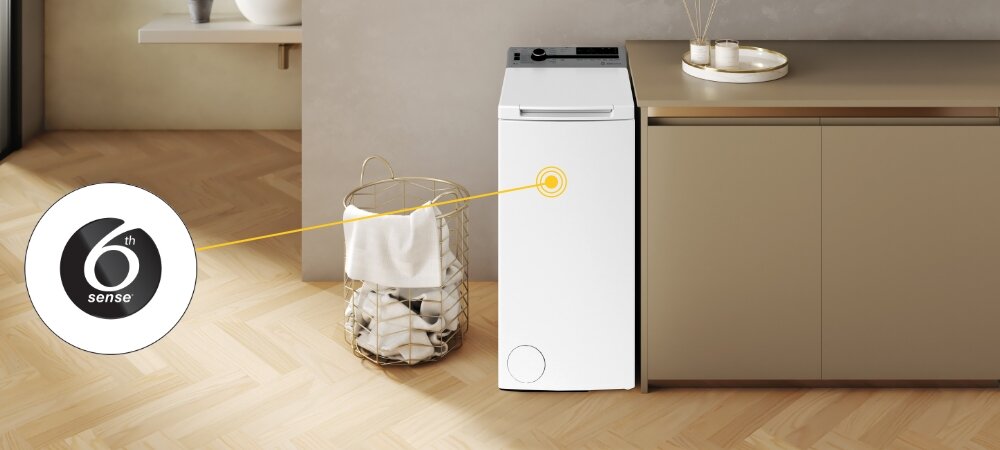 Na obrazie znajduje się biała pralka ustawiona obok szafki w jasnym pomieszczeniu. Obok pralki widoczny jest kosz z praniem, a na obrazie znajduje się logo z napisem \'6th sense\'.