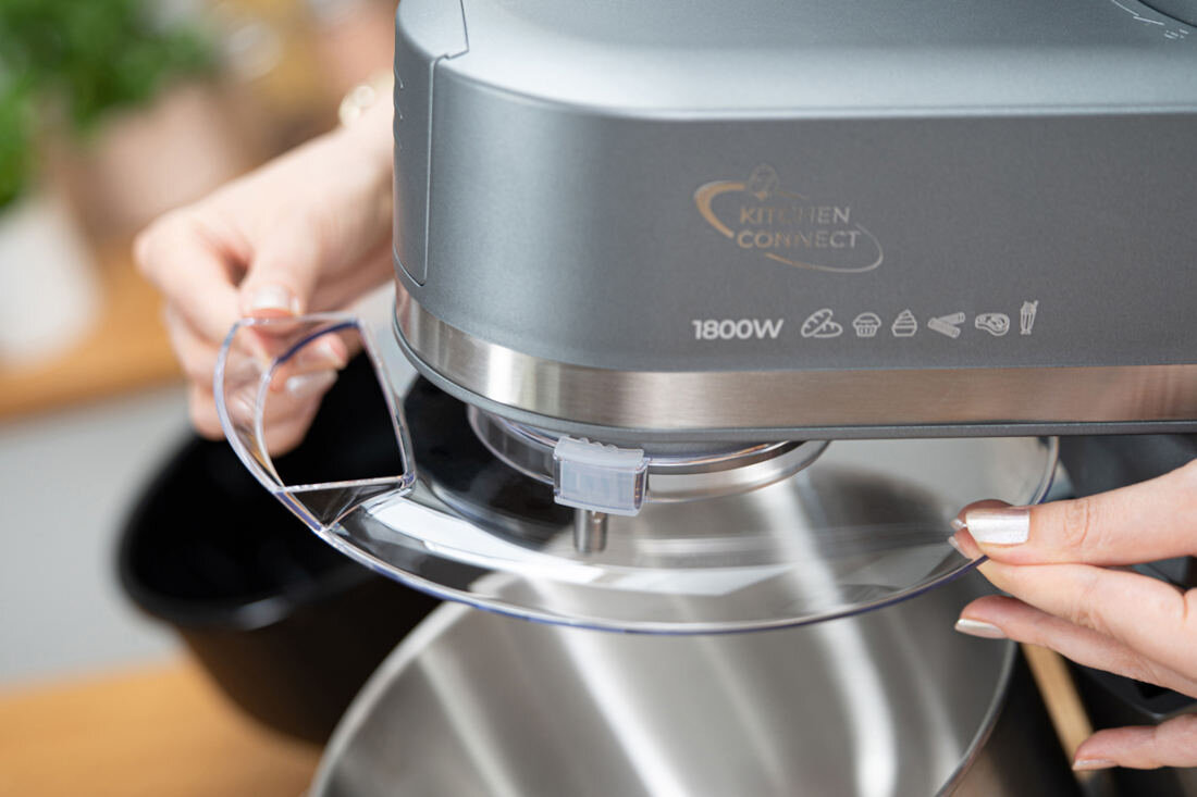 Osoba trzyma przezroczystą osłonę robota kuchennego planetarnego z widocznym napisem \'KITCHEN CONNECT\' oraz \'1800W\'.