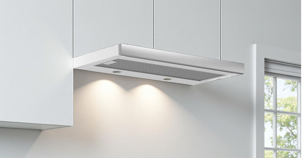 OKAP AKPO WK-7 Light Eco 60 Na zdjęciu 1.jpg przedstawiono kuchnię w czarno‑białej zabudowie z czarnym, szklanym okapem skośnym zawieszonym nad płytą grzewczą i piekarnikiem do zabudowy. Po prawej stronie widać lodówkę w kolorze inox oraz stół z wazonem czerwonych tulipanów, co dodaje aranżacji przytulnego charakteru