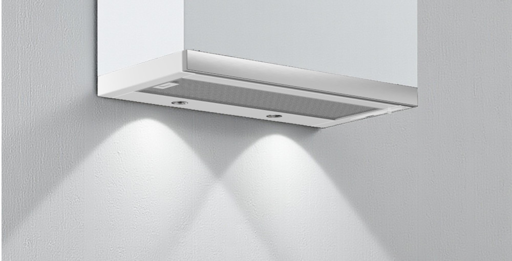 OKAP AKPO WK-7 Light Eco 60 Na zdjęciu 22.jpg widać jasną kuchnię z czarnym, szklanym okapem skośnym zamontowanym nad gazową płytą grzejną z czterema palnikami. Blat zdobi doniczka z rośliną oraz deski do krojenia i owoce, co podkreśla minimalistyczny, elegancki wystrój wnętrza