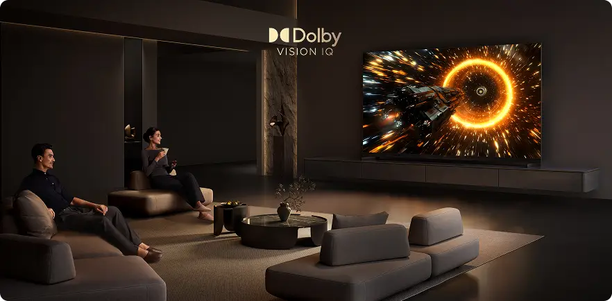 W przestronnym salonie znajduje się duży telewizor wyświetlający dynamiczną scenę z kosmicznym statkiem i jasnym, pomarańczowym pierścieniem. Na ekranie widoczny jest napis \'Dolby Vision IQ\'.