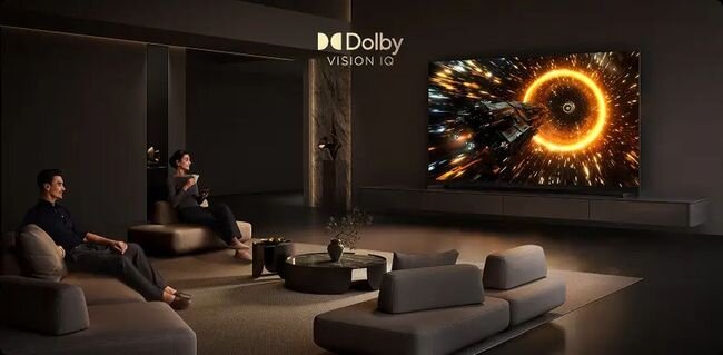 W przestronnym salonie znajduje się duży telewizor wyświetlający dynamiczną scenę z efektem świetlnym. Na ekranie widnieje logo \'Dolby Vision IQ\'.