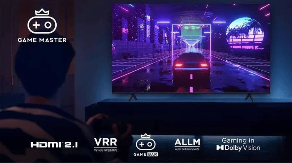 Telewizor TCL 55T69C - Oosba siędząca na kanapie z kontrolerem w ręku, telewizor stojący na komodzie w pomieszczeniu