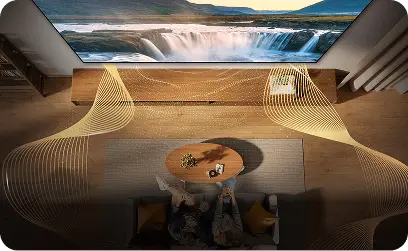 Widok z góry na parę na kanapie; złote fale wokół telewizora symbolizują dźwięk przestrzenny Dolby Atmos