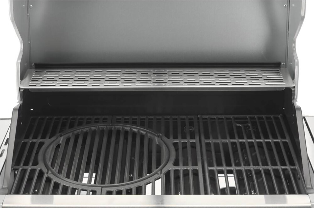 Zdjęcie przedstawia wnętrze grilla gazowego z otwartą pokrywą. Widać ruszt z okrągłym otworem na środku oraz półkę na górze z perforowaną powierzchnią.