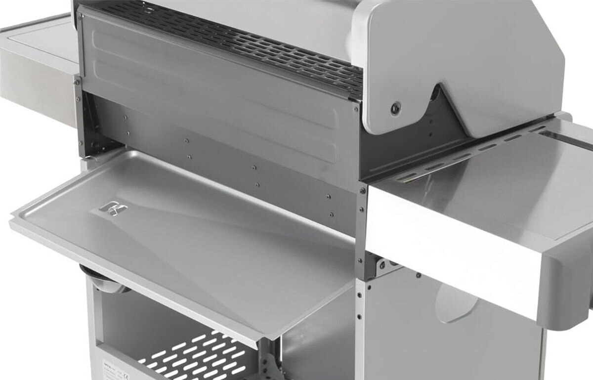 Zdjęcie przedstawia fragment metalowego grilla gazowego z otwartą pokrywą i bocznymi półkami. Widać kratkę do grillowania oraz dolną półkę z otworami.