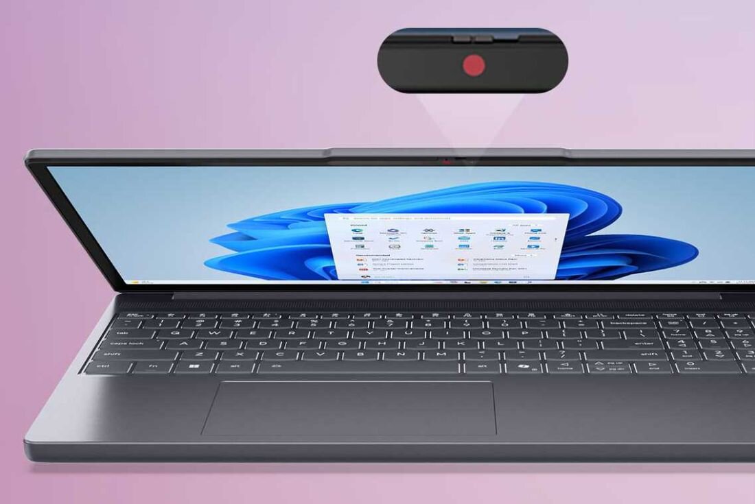 Laptop z otwartym ekranem wyświetlającym interfejs systemu Windows 11. Nad ekranem widoczny jest zbliżony obraz kamery z czerwonym punktem wskazującym na funkcję prywatności.