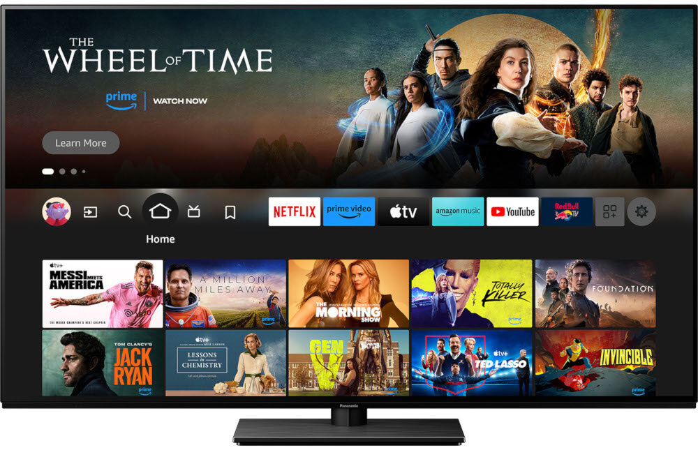 Telewizor wyświetla ekran główny z aplikacjami takimi jak Netflix, Prime Video, Apple TV, Amazon Music i YouTube. Na górze ekranu widoczny jest baner z napisem \'The Wheel of Time\' oraz postaciami z serialu.