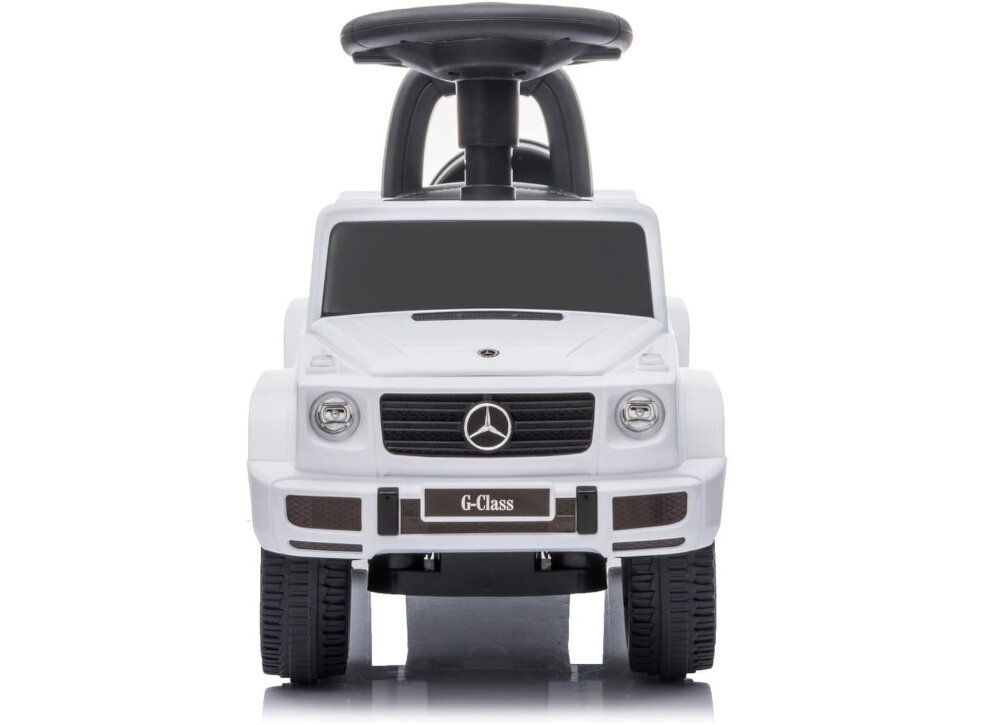 Na zdjęciu widoczny jest biały jeździk w kształcie samochodu z logo Mercedes na przodzie. Na tablicy rejestracyjnej widnieje napis \'G-Class\'.