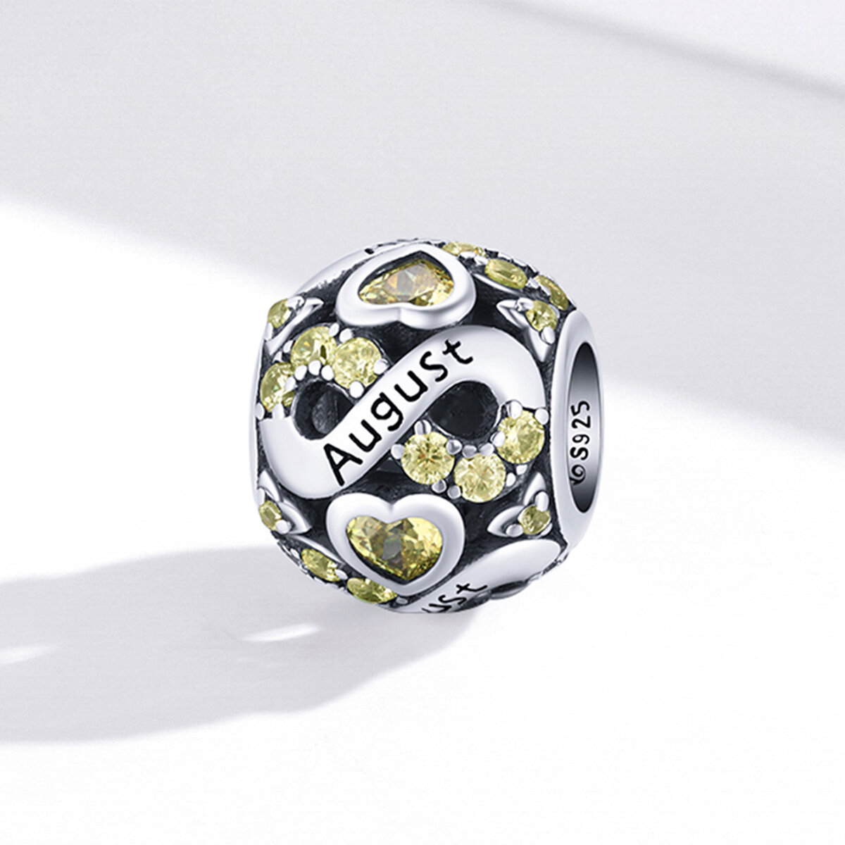Srebrny charms z napisem \'August\' ozdobiony żółtymi kamieniami i sercami. Na boku widoczny jest napis \'S925\'.