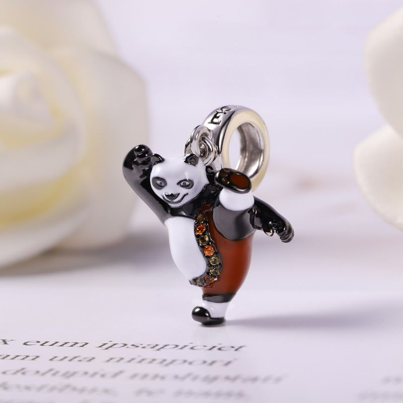 Zawieszka charms przedstawiająca pandę w dynamicznej pozie, z uniesioną nogą i ręką. Panda ma biało-czarne wykończenie z brązowymi elementami i ozdobnymi kamieniami na pasie.