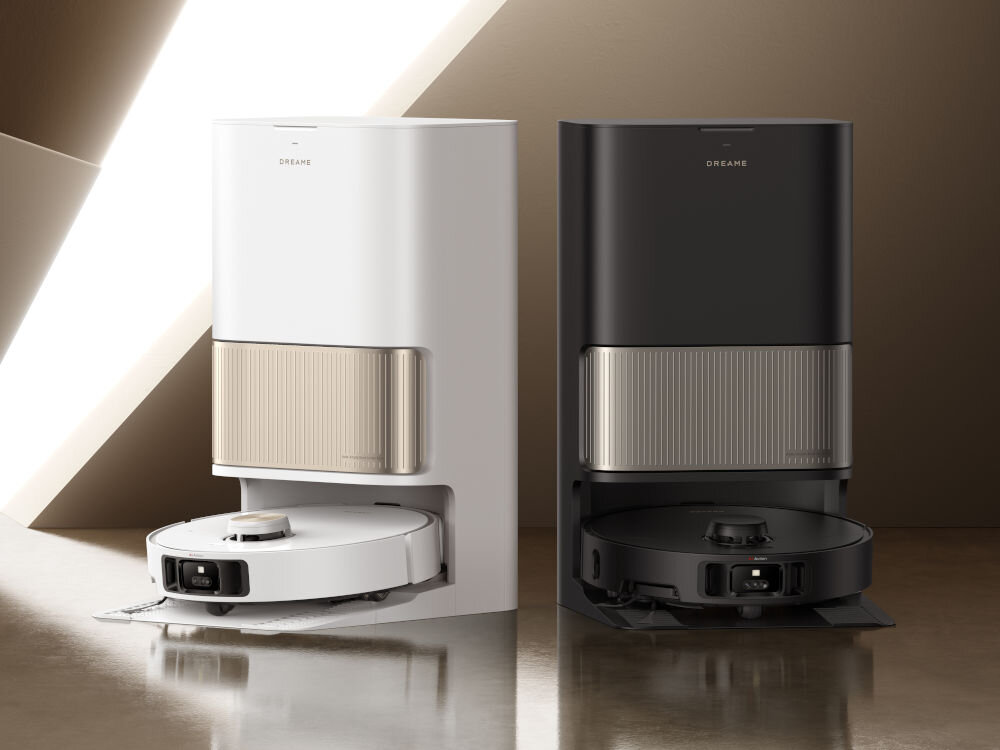 Na obrazie znajdują się dwa roboty sprzątające w stacjach dokujących, jeden biały, drugi czarny. Na obu stacjach widoczne jest logo \'DREAME\'.