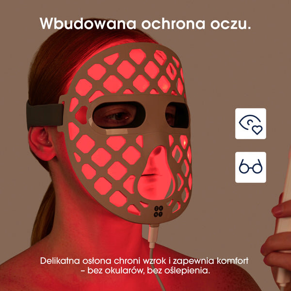 Osoba nosi białą maskę LED z czerwonym światłem, z otworami na oczy i usta. Tekst na obrazie: \'Wbudowana ochrona oczu. Delikatna osłona chroni wzrok i zapewnia komfort - bez okularów, bez oślepienia.\'