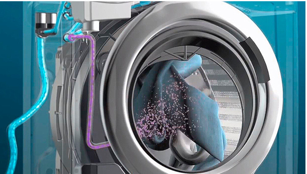 Obraz przedstawia wnętrze bębna pralki z widocznym niebieskim materiałem i różowymi cząsteczkami. W tle widoczne są elementy techniczne pralki oraz rury z niebieskim i różowym płynem.
