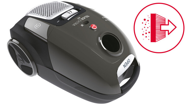 Odkurzacz w kolorze ciemnoszarym z widocznym napisem \'TELIOS EXTRA\' oraz przyciskiem z logo producenta. Obok znajduje się czerwony symbol filtra z cząsteczkami i strzałką.