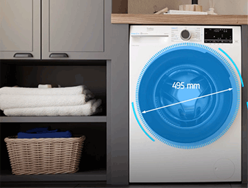 Pralka w zabudowie z widocznym napisem \'495 mm\' na drzwiach bębna. Obok znajduje się półka z ręcznikami i koszem wiklinowym.