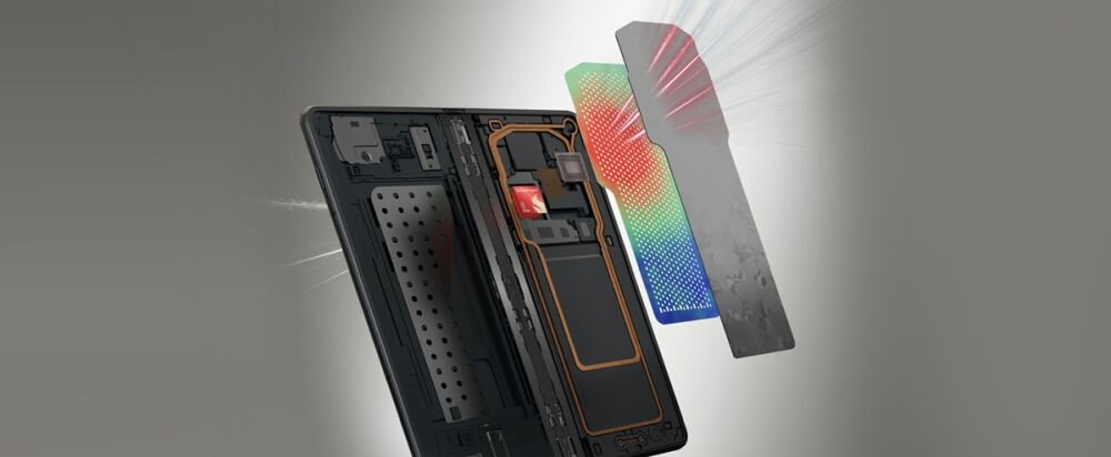 Obraz przedstawia rozłożony smartfon z widocznymi wewnętrznymi komponentami oraz kolorowymi elementami obok. Tło jest szare, a całość ma techniczny charakter.