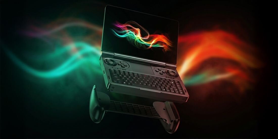 Obraz przedstawia laptop z otwartym ekranem i klawiaturą, z widocznymi kolorowymi smugami w tle. Laptop ma wbudowane kontrolery po bokach klawiatury.