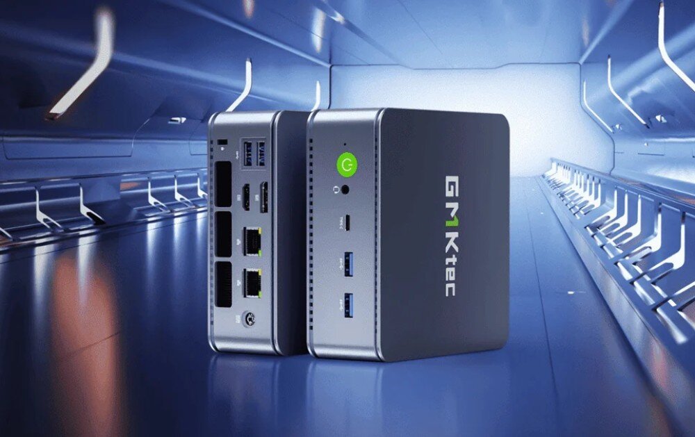 Dwa komputery mini PC marki GMKtec stoją obok siebie na tle futurystycznego korytarza. Na jednym z urządzeń widoczne są porty USB, HDMI i Ethernet, a na drugim logo GMKtec oraz przycisk zasilania.