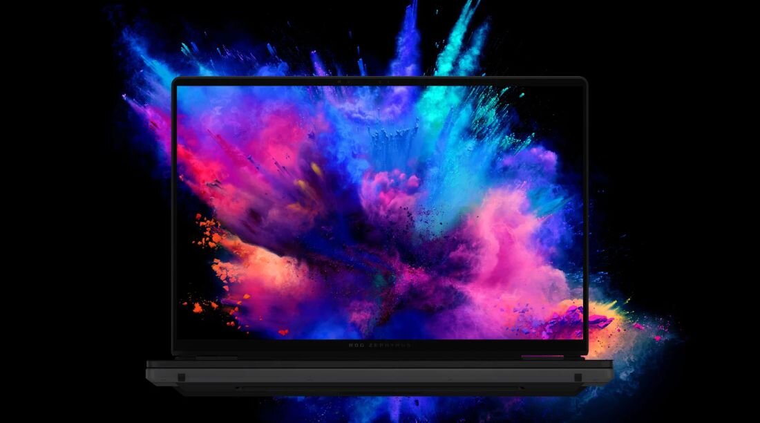 Laptop z wyświetlaczem pokazującym kolorową eksplozję barw na czarnym tle. Na dolnej ramce ekranu widoczny jest napis \'ROG Zephyrus\'.