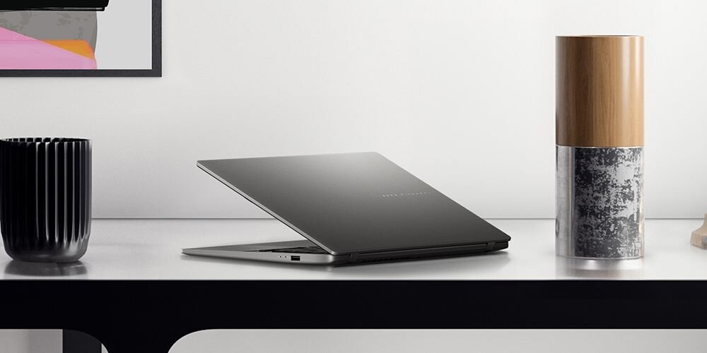 Laptop ASUS Vivobook S14 na stole obok wazonu z kwiatami lub czarnej, żłobkowanej filiżanki .   - Wzornictwo metaliczne wykończenie 