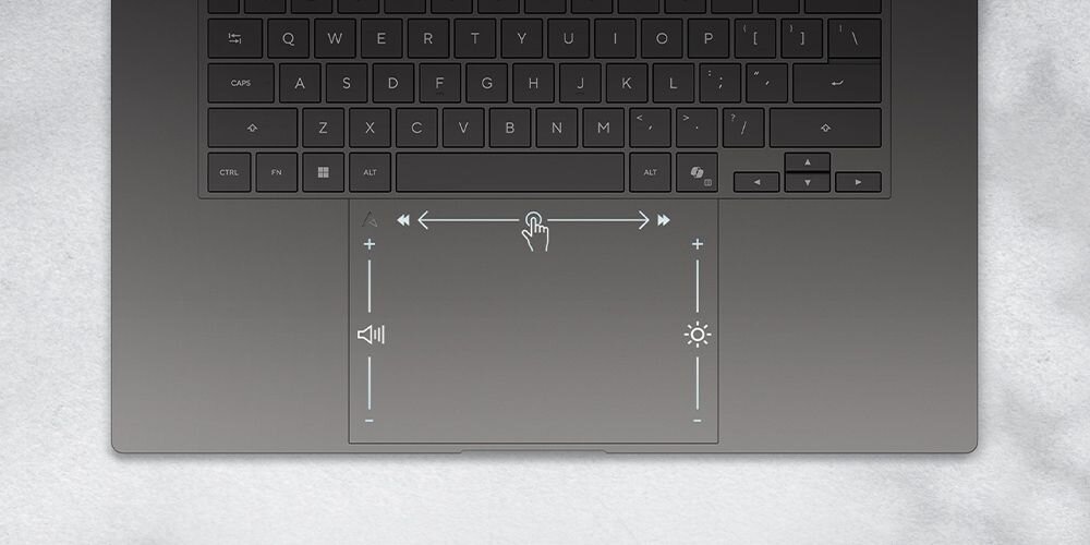 Obraz przedstawia klawiaturę laptopa z widocznym touchpadem. Na touchpadzie znajdują się ikony regulacji głośności i jasności oraz symbol dotyku.