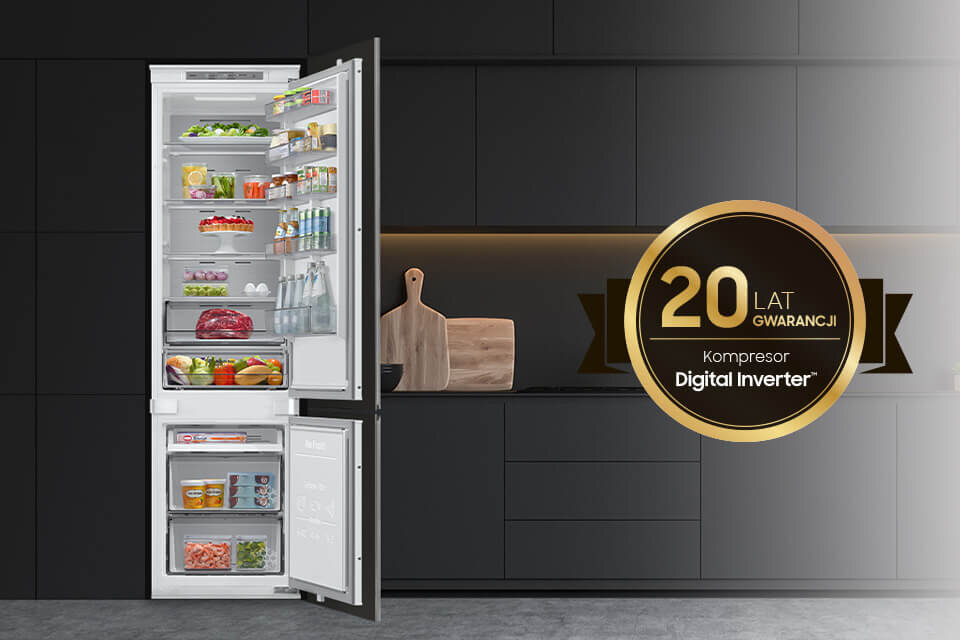 Otwarta lodówka z widocznymi produktami spożywczymi, obok której znajduje się okrągły znak z napisem \'20 LAT GWARANCJI Kompresor Digital Inverter\'. W tle widoczna jest ciemna kuchnia z deską do krojenia i naczyniami.