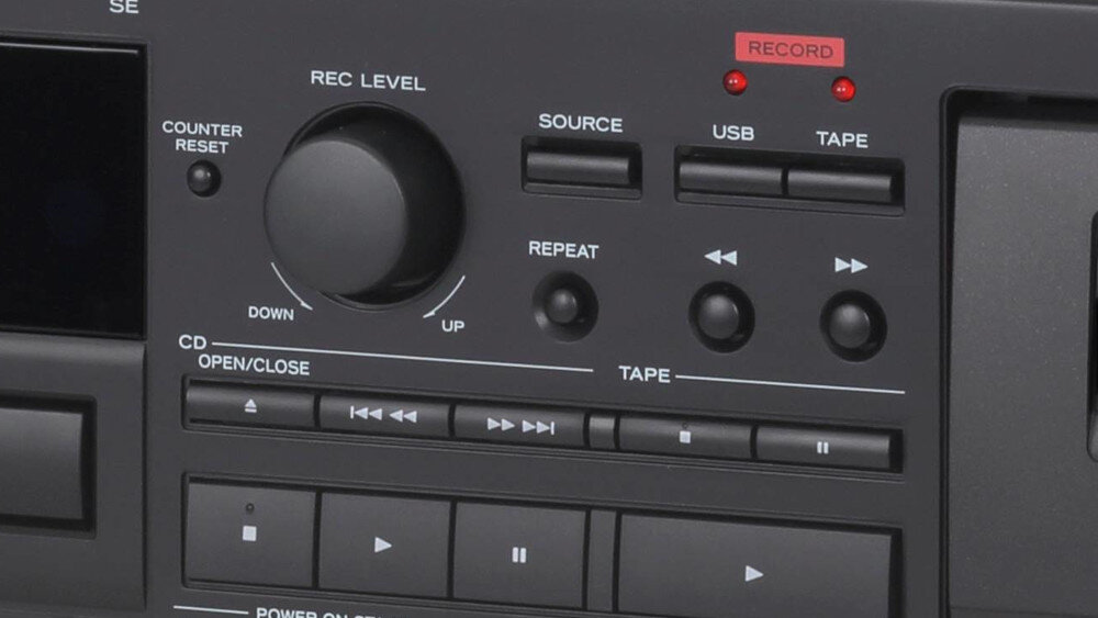 Panel sterowania urządzenia z widocznymi przyciskami i pokrętłem oznaczonym jako \'REC LEVEL\'. Widoczne są napisy: \'COUNTER RESET\', \'SOURCE\', \'USB\', \'TAPE\', \'REPEAT\', \'CD OPEN/CLOSE\', oraz \'RECORD\'.