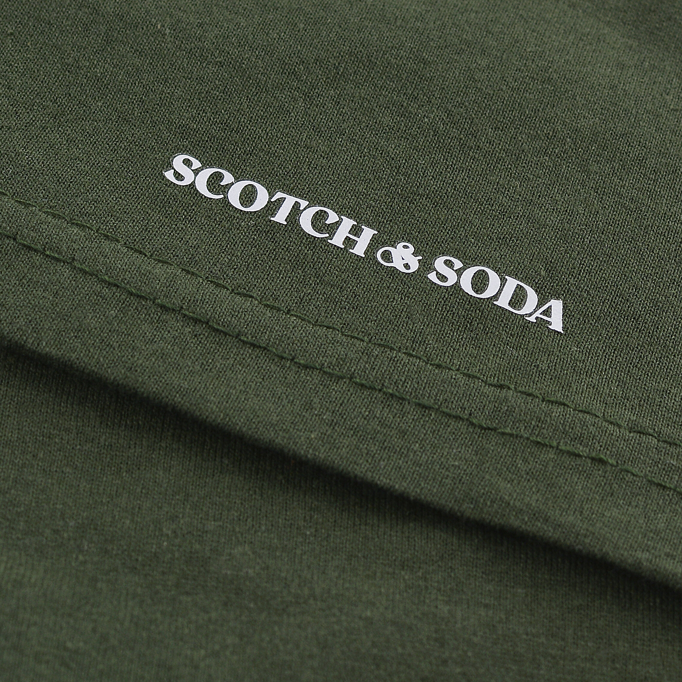 Zielona tkanina z białym napisem \'SCOTCH & SODA\'.