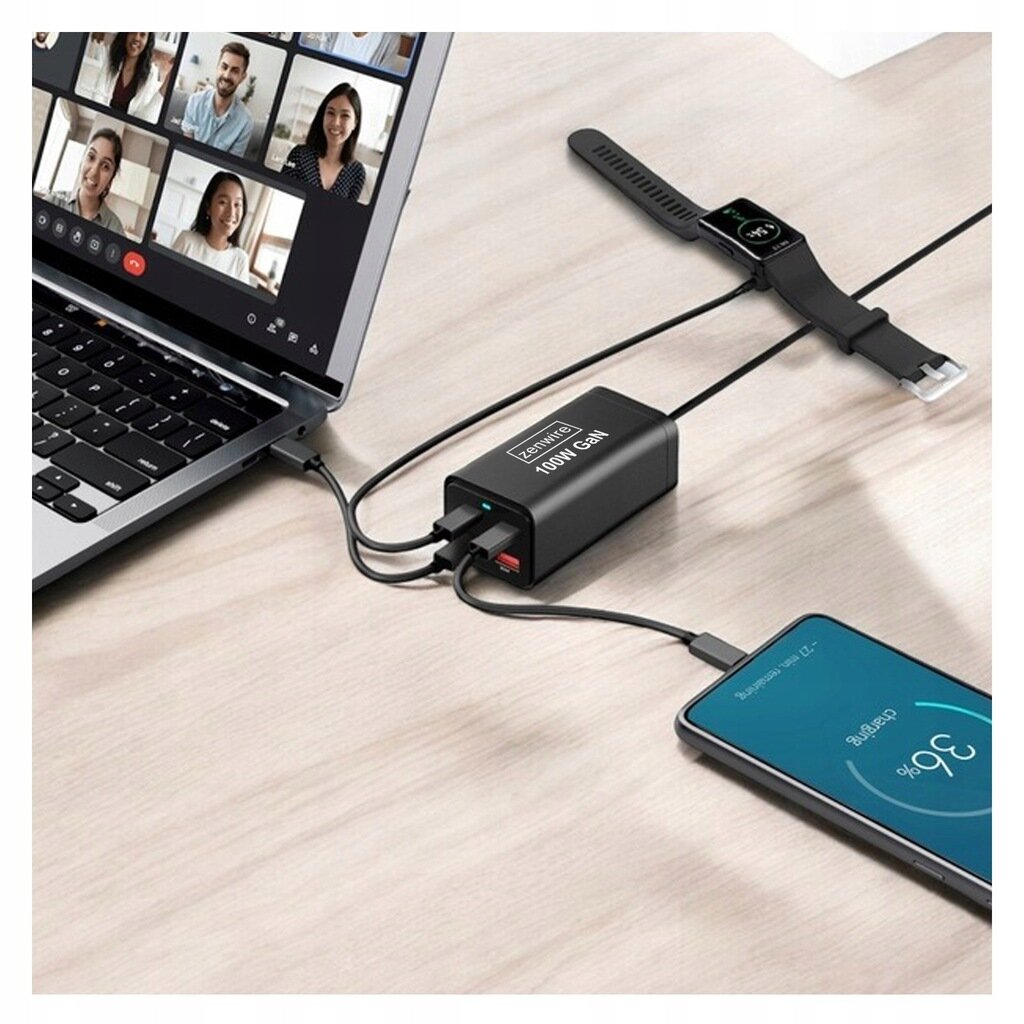 Na biurku znajduje się laptop z otwartym ekranem, obok którego leży czarny zasilacz z napisem \'Zenwire 100W GaN\'. Zasilacz jest podłączony do laptopa, smartfona i smartwatcha za pomocą kabli.