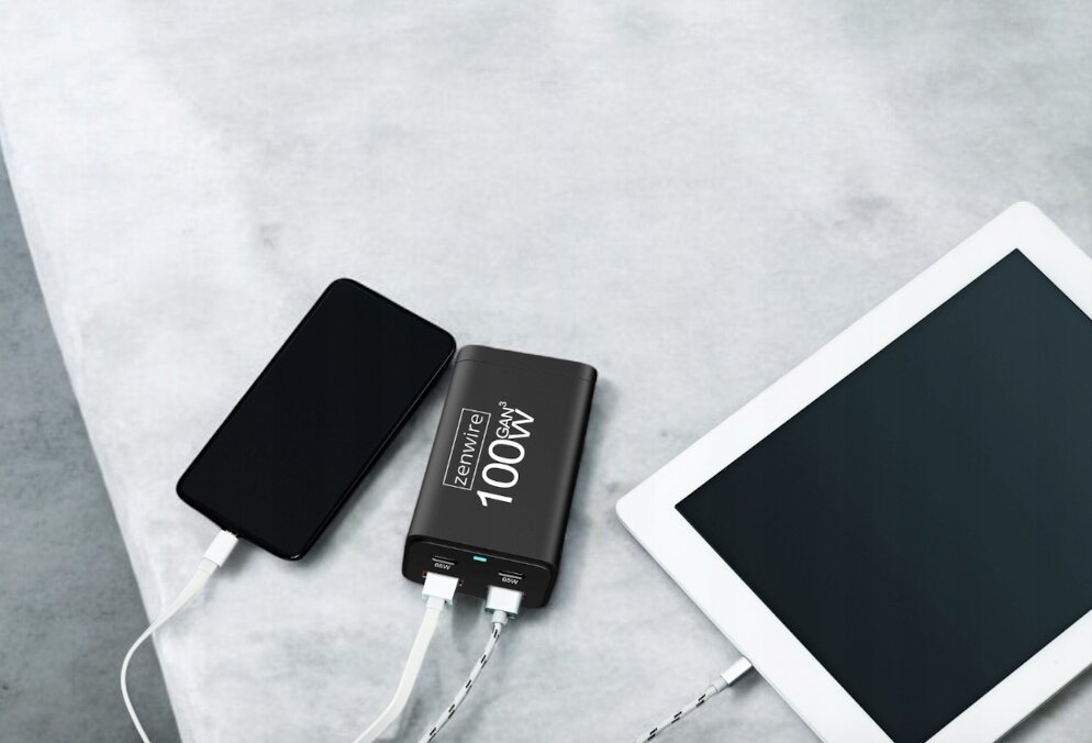 Na obrazie widać ładowarkę sieciową Zenwire 100W GAN, do której podłączone są dwa urządzenia: smartfon i tablet. Ładowarka ma dwa porty USB-C i dwa porty USB-A.