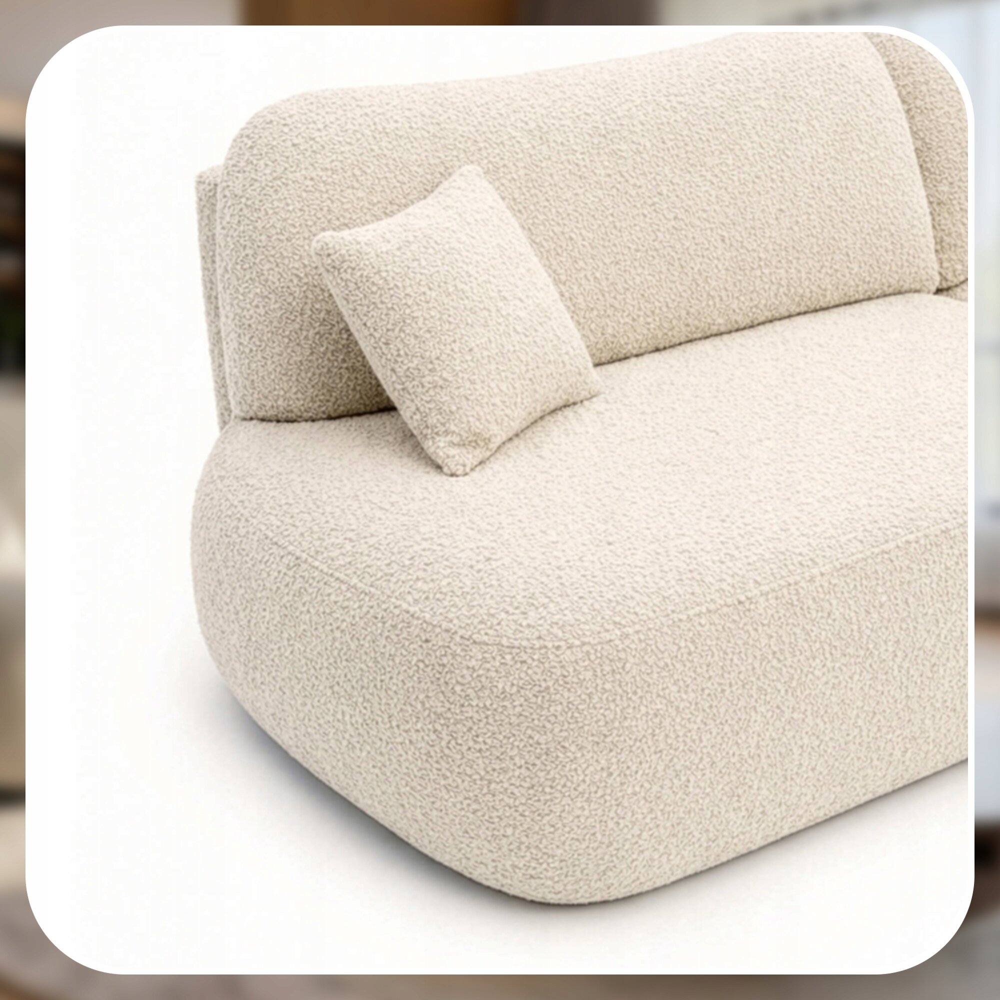 Kremowa sofa z zaokrąglonymi krawędziami i poduszką w tym samym kolorze. Materiał wygląda na miękki i teksturowany.