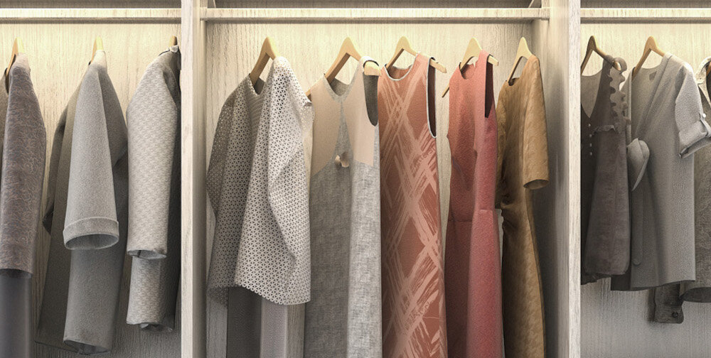 Wnętrze szafy z ubraniami na wieszakach, w tym różne koszule i sukienki w odcieniach szarości i brązu. Ubrania są starannie ułożone, a tło stanowi jasna, drewniana powierzchnia.