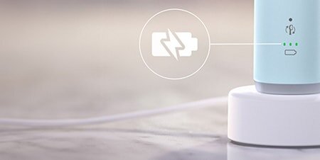 Obraz przedstawia niebieską szczoteczkę soniczną na białej podstawce ładującej. Obok szczoteczki widoczna jest ikona baterii z symbolem ładowania i trzema zielonymi diodami.